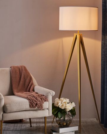 a tripod floor lamp brings light to a cozy reading nook