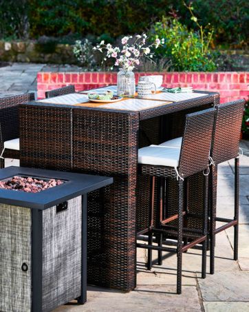 a high table and chairs with place settings for 4 guests is set on a backyard patio