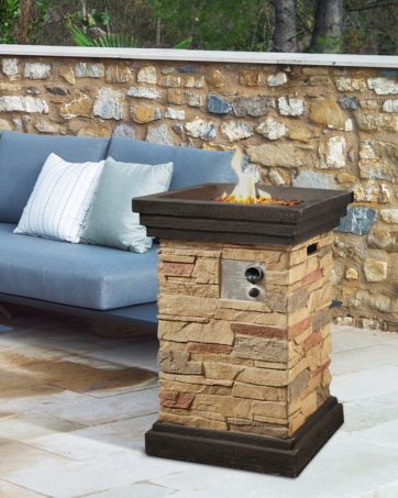 a square shaped fire pit sits beside a pool and lounge chair outside